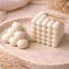 Mehurčki kolekcija II – dve beli sveči v obliki kocke in piramide z mehurčkasto strukturo